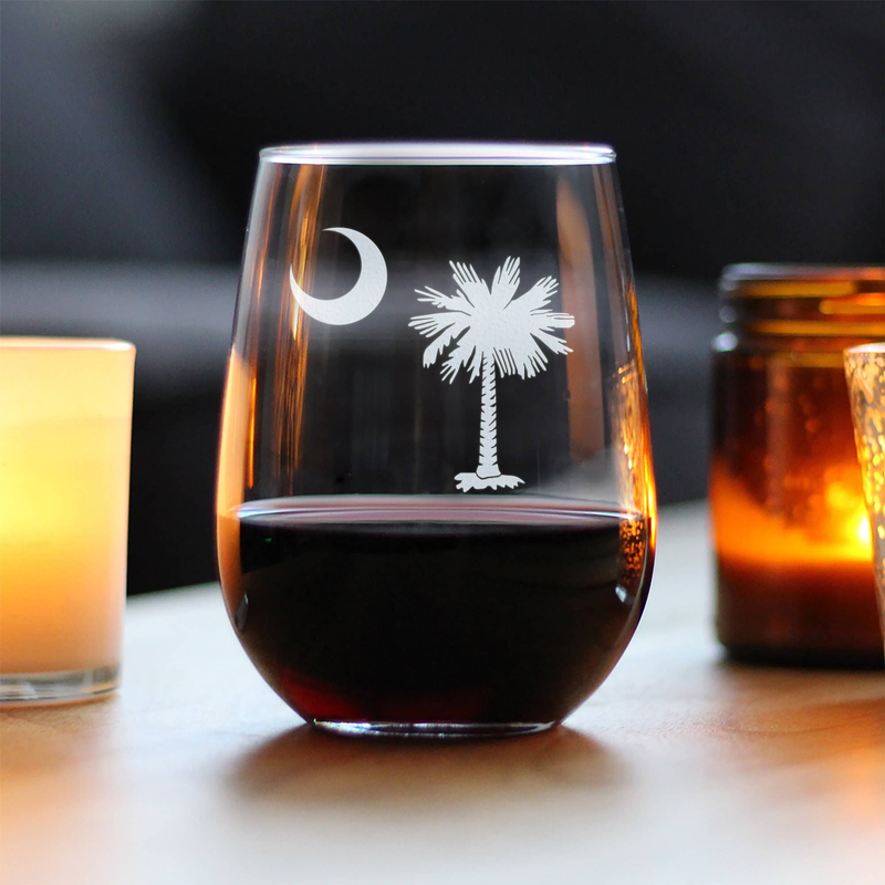 Clear stemless wine glass with etched moon and palm tree, filled with red wine.