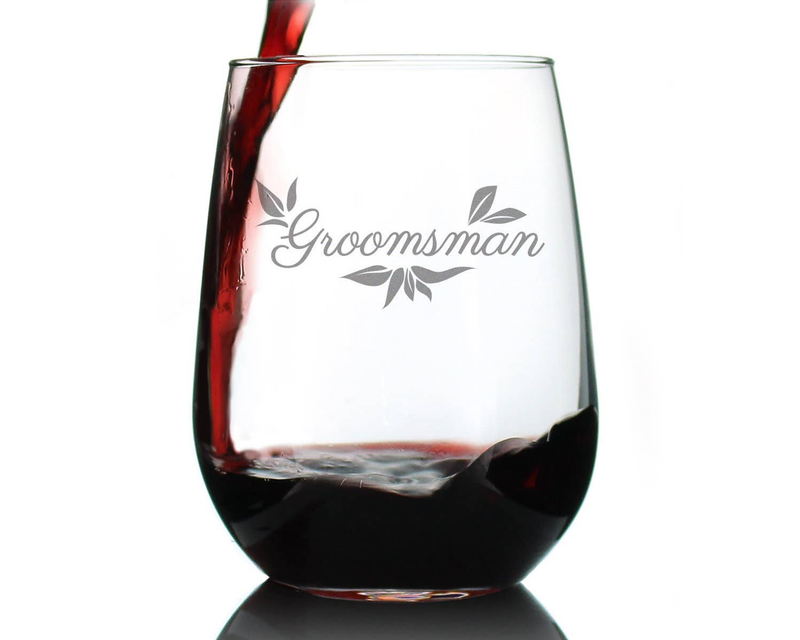Stemless wine glass with Groomsman script and floral etching, filled with red wine