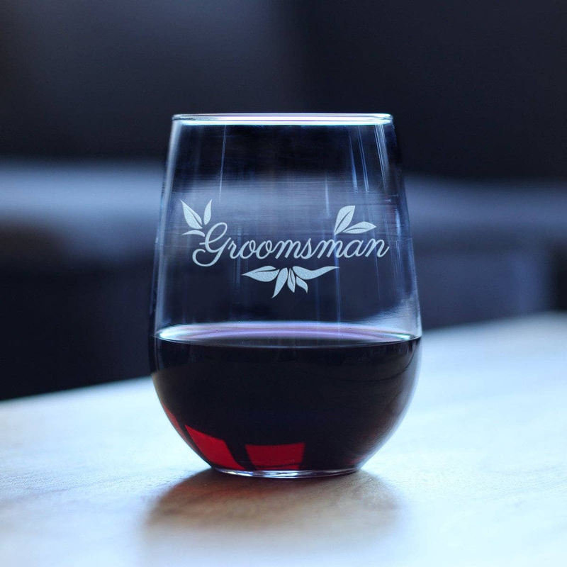 Stemless wine glass on tabletop with Groomsman script and floral etched design