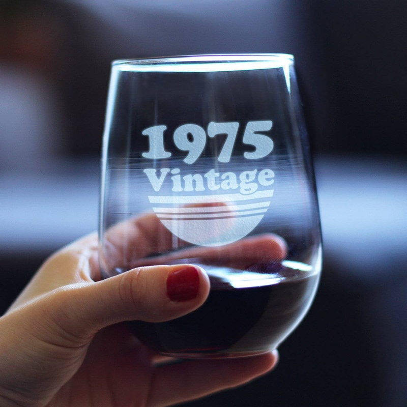 Hand holding a stemless wine glass with 1975 Vintage etched logo