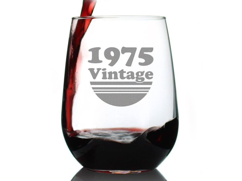 Stemless wine glass with 1975 Vintage etched design and dark red wine