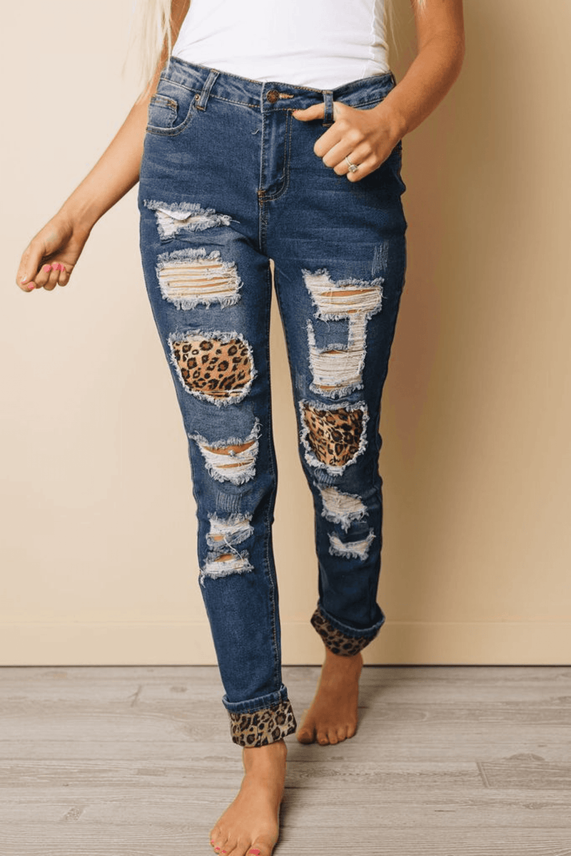 Distressed blue denim jeans with ripped knees and leopard-print cuffs at hems