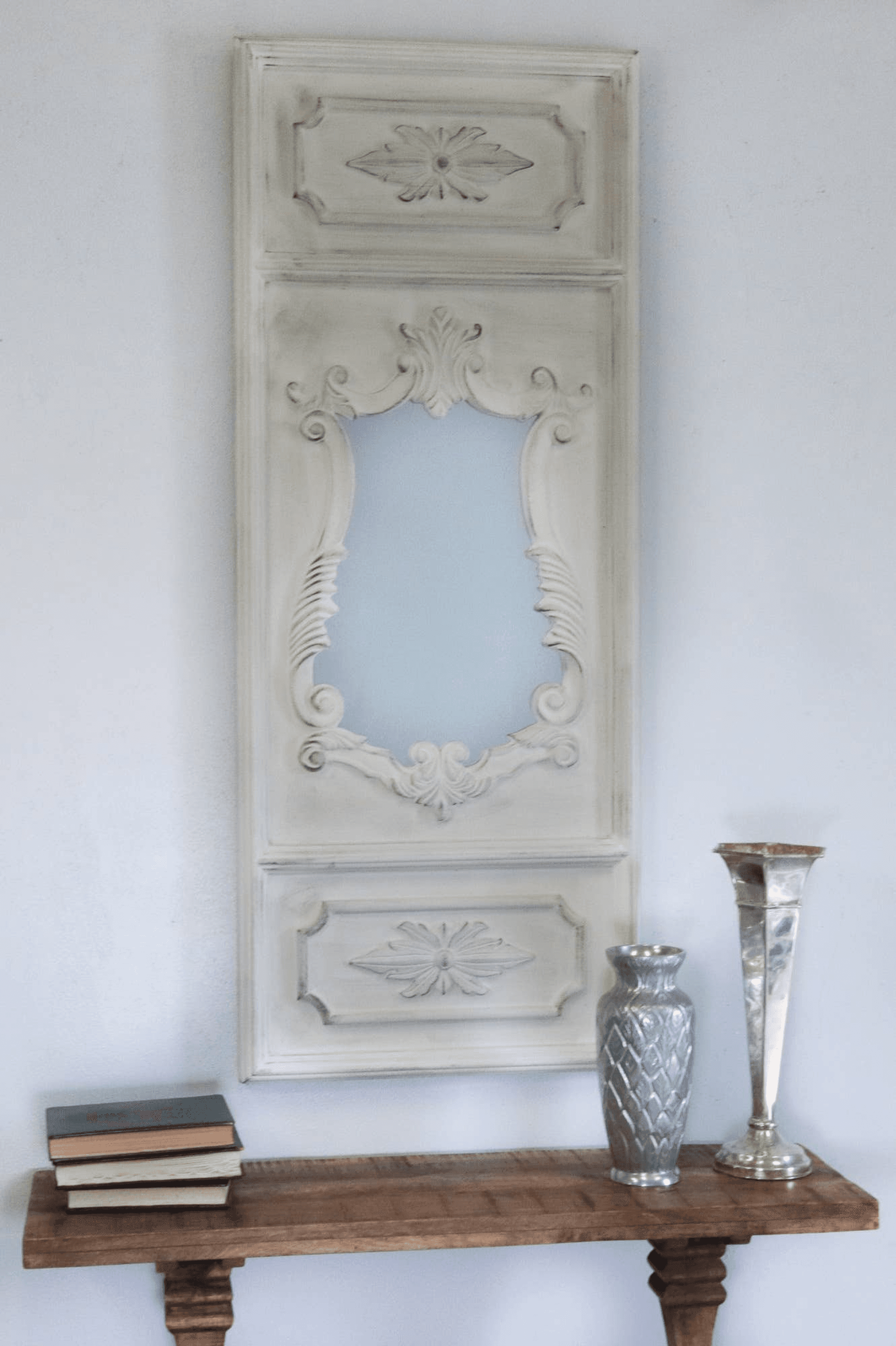 White ornate vertical wall mirror with carved scrollwork and floral accents