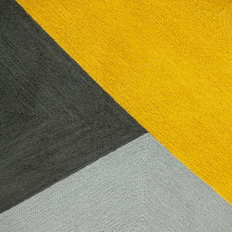 Close-up multicolor pillow cover fabric: gray, yellow, and white diagonal panels