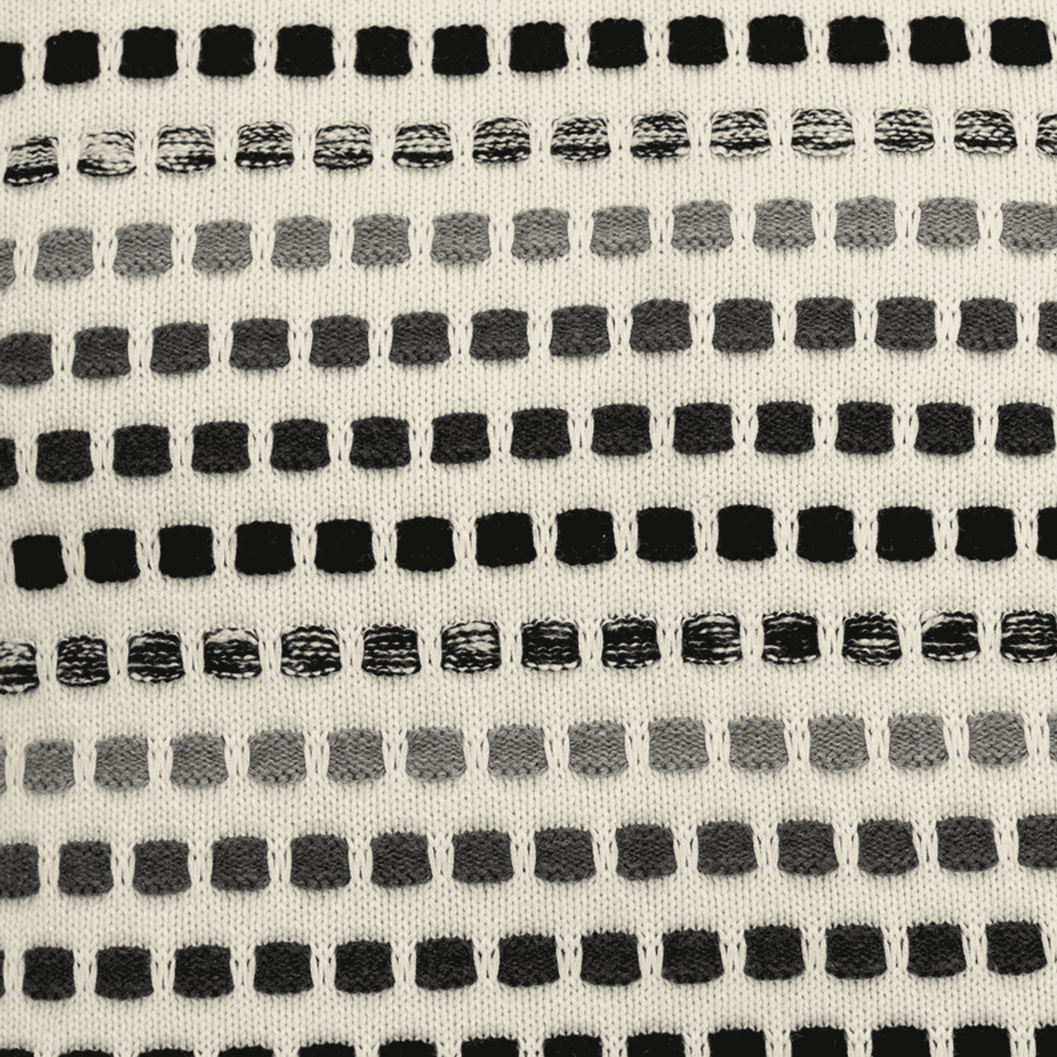 Beige throw pillow fabric close-up with black and white horizontal dots and stitching