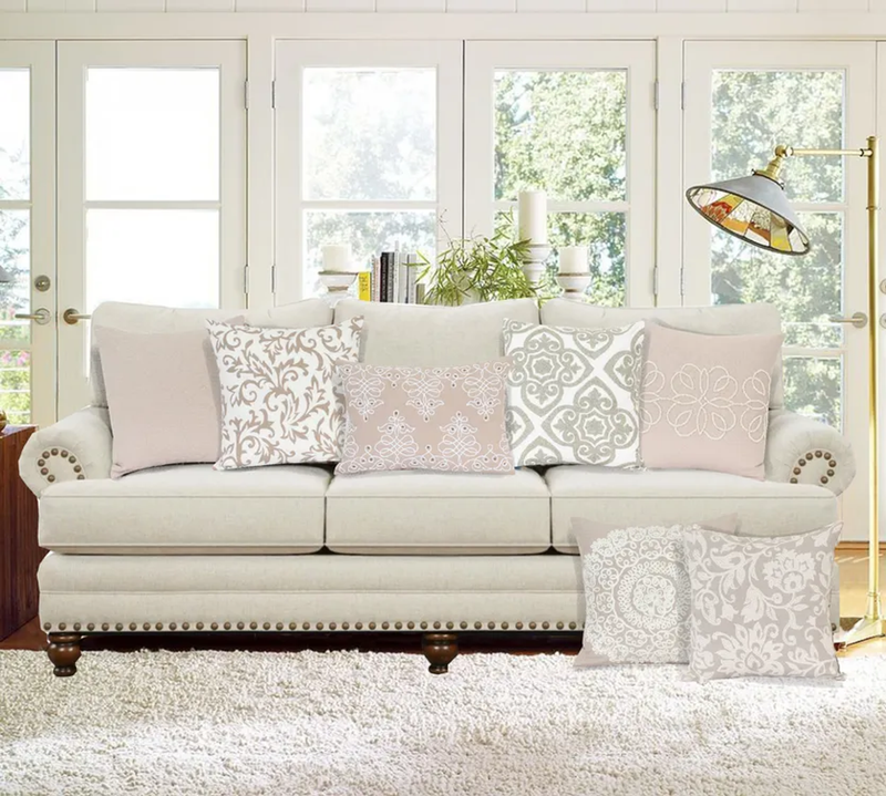 Set of beige throw pillows on sofa, including quilted square pillow