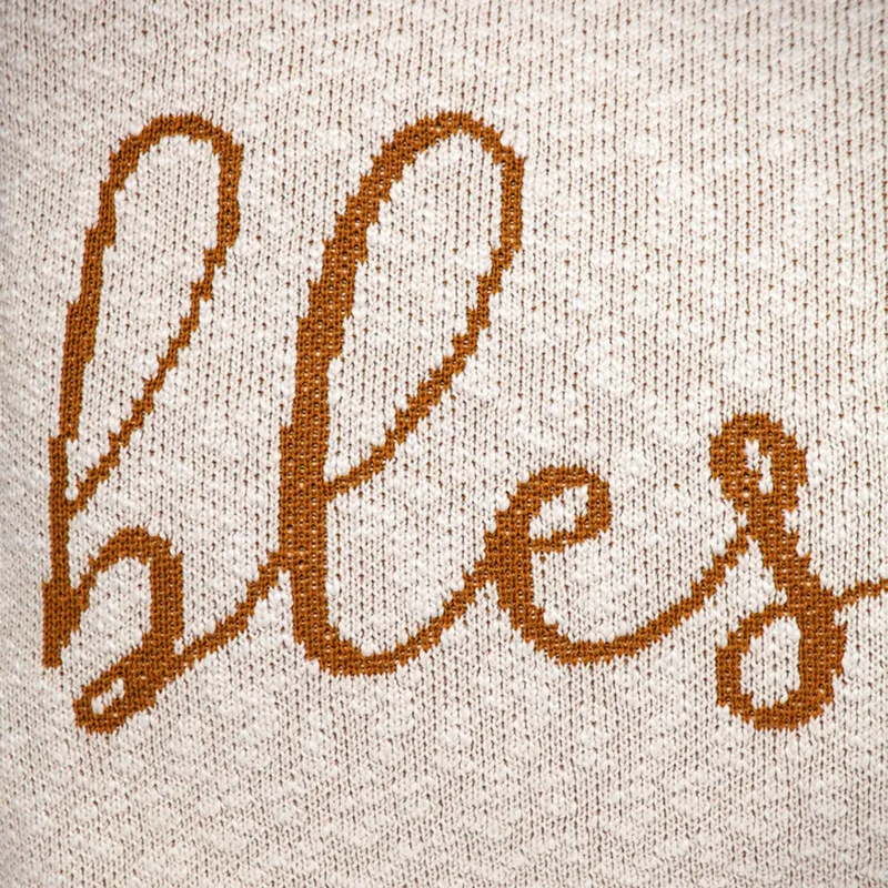Beige throw pillow close-up of embroidered 'Blessed' text
