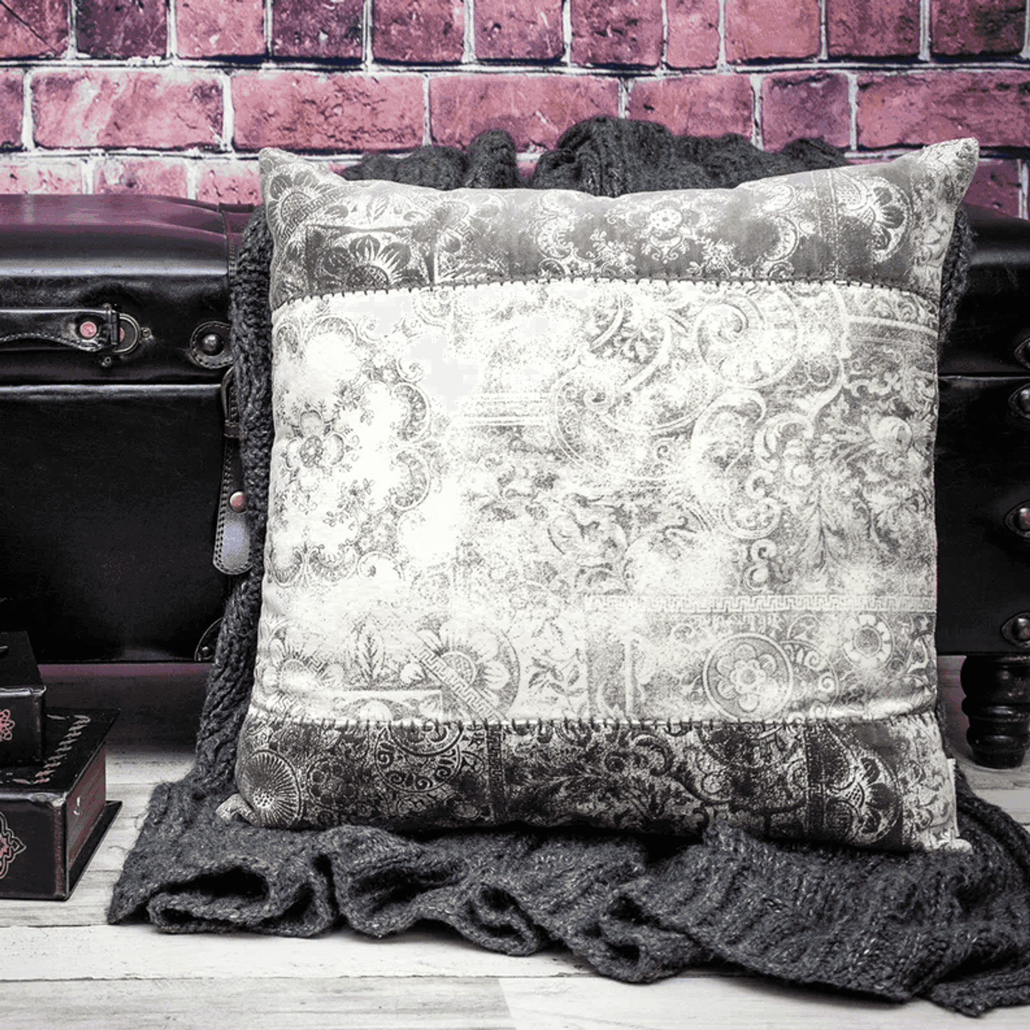 Gray and white ornate print throw pillow with dark textured border and piping detail.