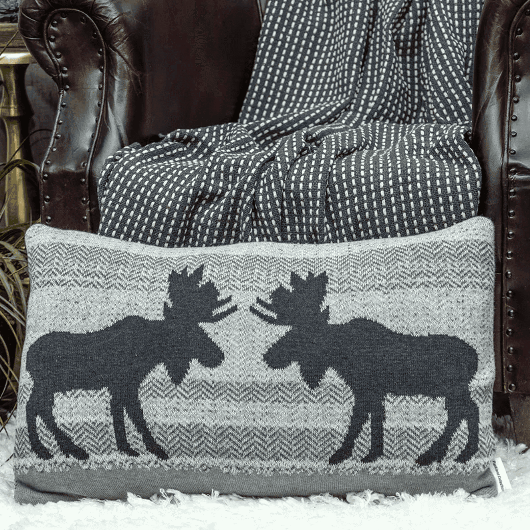 Gray knit throw pillow with black-and-white buck silhouettes and fringe trim