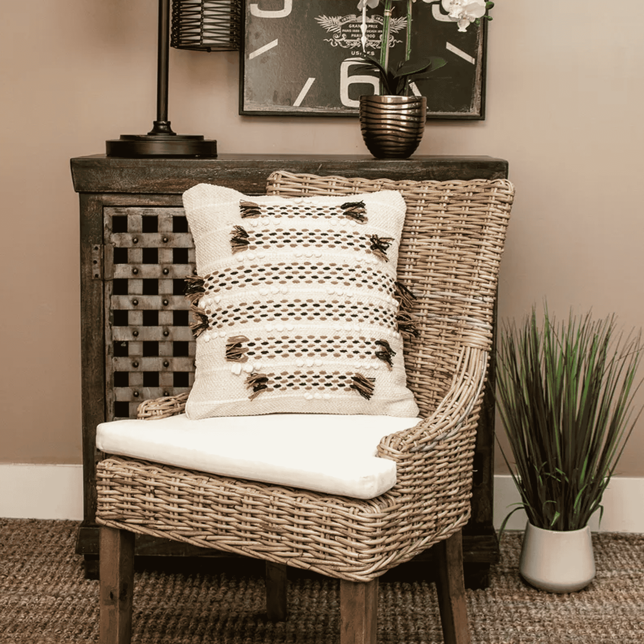 Beige patterned throw pillow with geometric dots and fringe tassels on chair seat