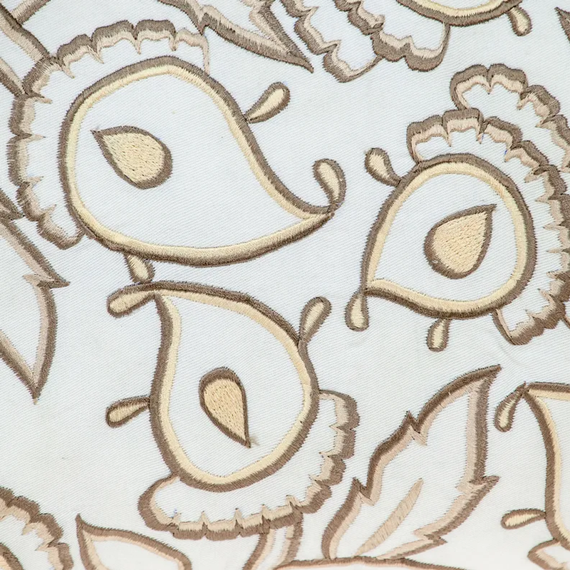 Close-up of white pillow cover with tan and brown embroidered bird motif