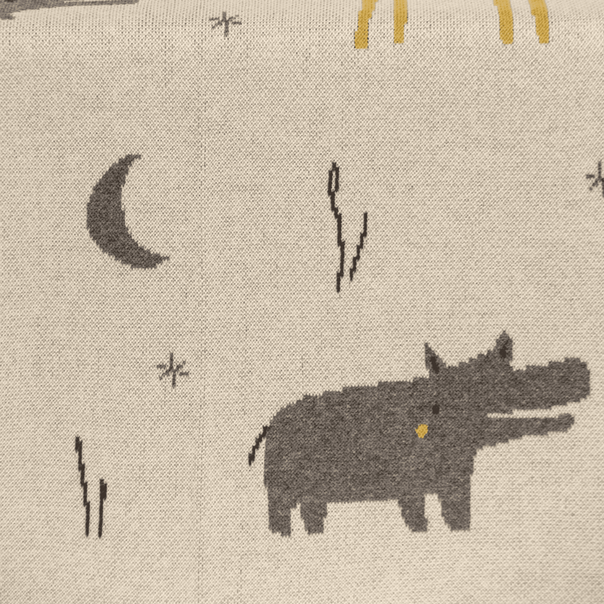Beige knit baby blanket close-up with moon, lightning marks and animal silhouettes