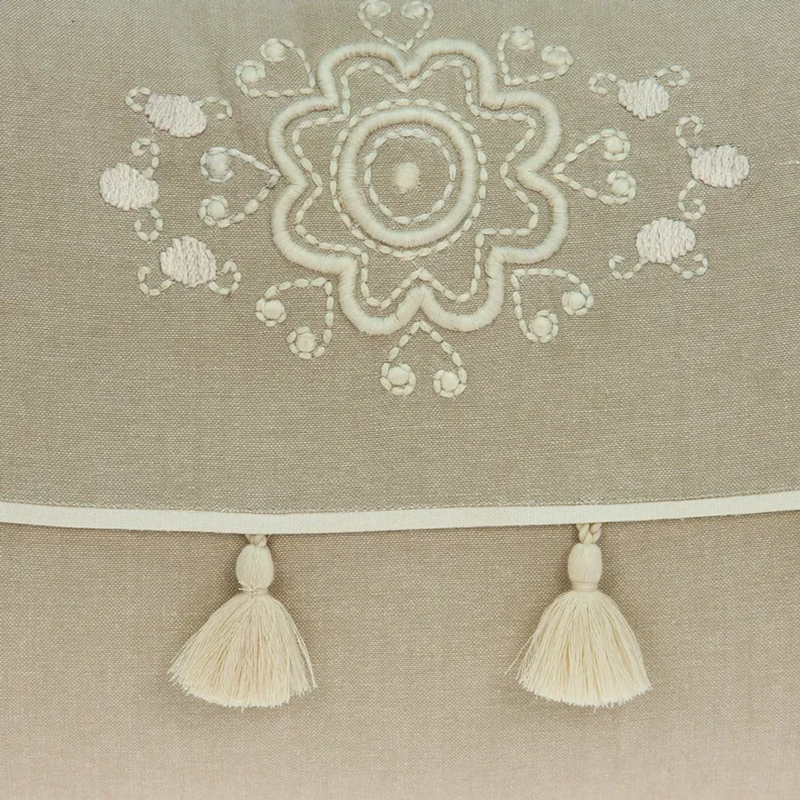 Beige throw pillow with stitched floral medallion and white tassel trim