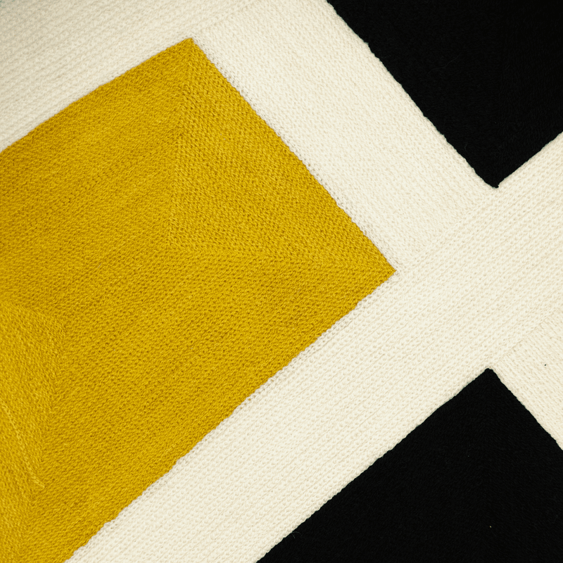 Detail view of contemporary pillow cover fabric: yellow diamond and white X stitching on black