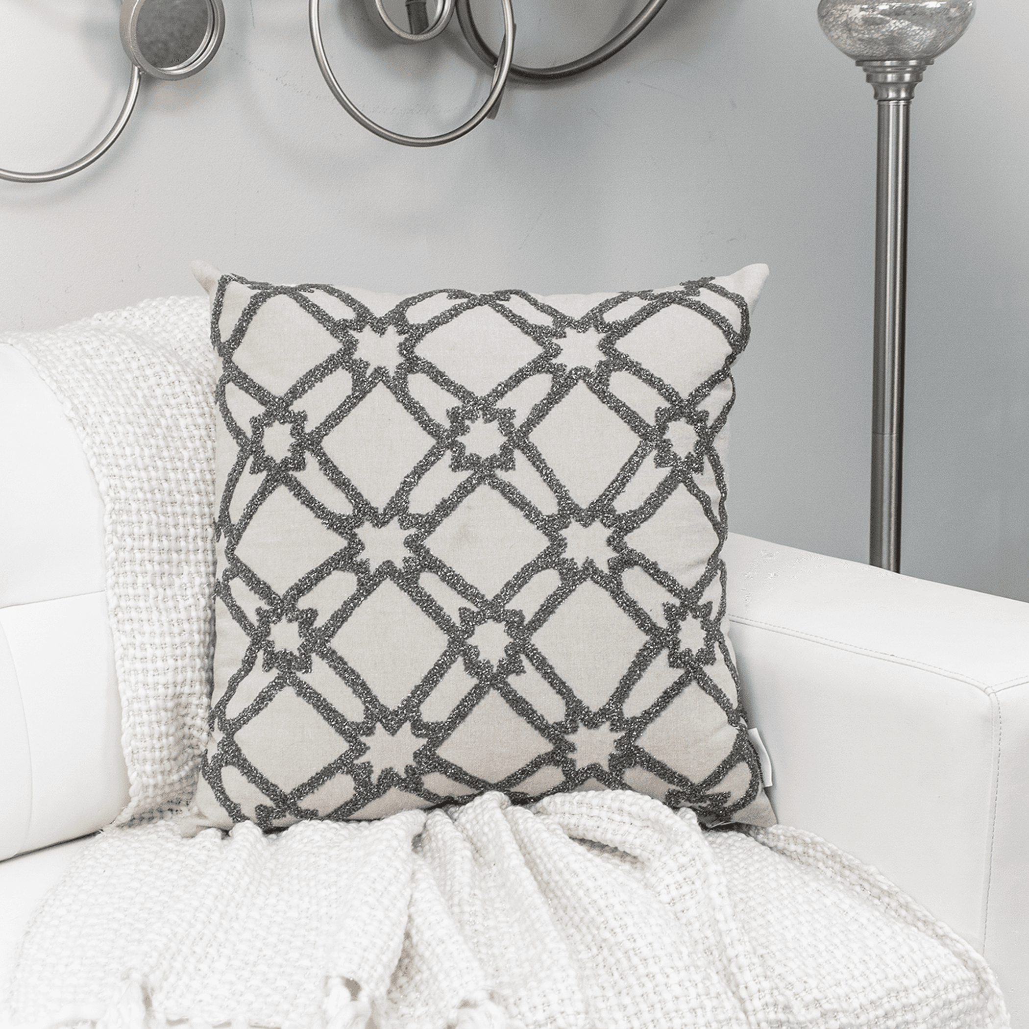 Beige throw pillow with dark gray geometric lattice embroidery pattern