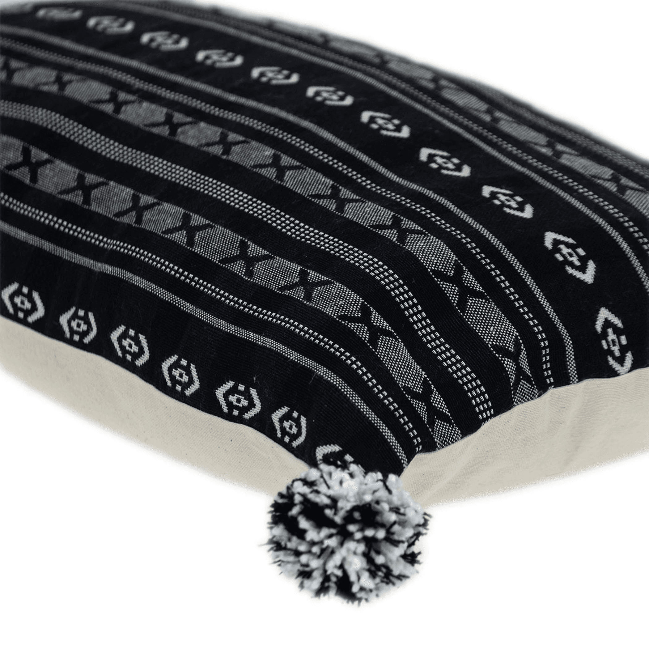 Black patterned throw pillow corner with pom-pom trim and stitched fabric detail
