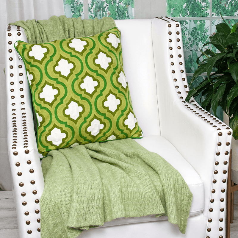 Green patterned throw pillow with white clover quatrefoil motifs and visible piping