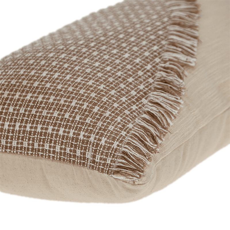 Close-up of woven pillow with dark-brown grid face, fringe trim, and beige backing