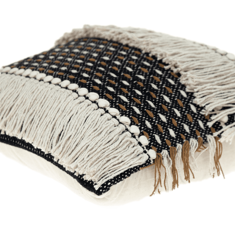 Black throw pillow close-up with white pom-pom border and woven fringe