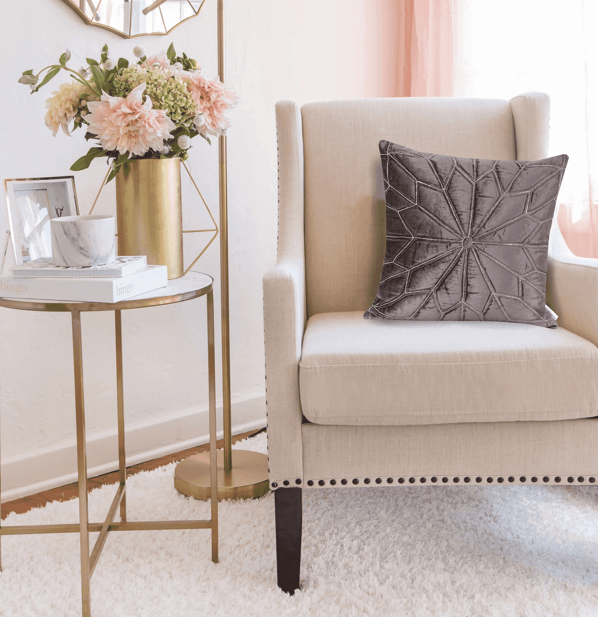 Gray geometric throw pillow with embroidered fan pattern, styled on a beige chair.