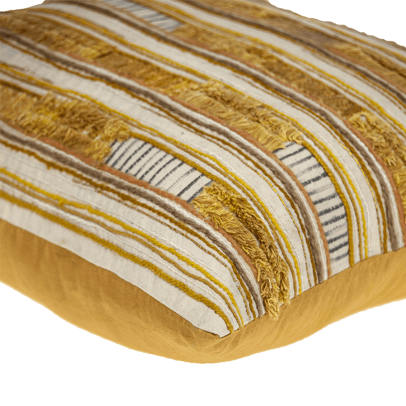 Close-up of frayed multicolor stripes on textured pillow cover in gold and cream