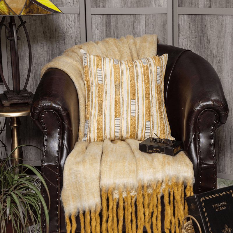 Multicolor striped pillow cover on dark leather chair arm, gold and cream stripes