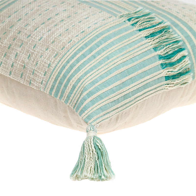 Cream throw pillow with mint-striped top panel and hanging tassel trim
