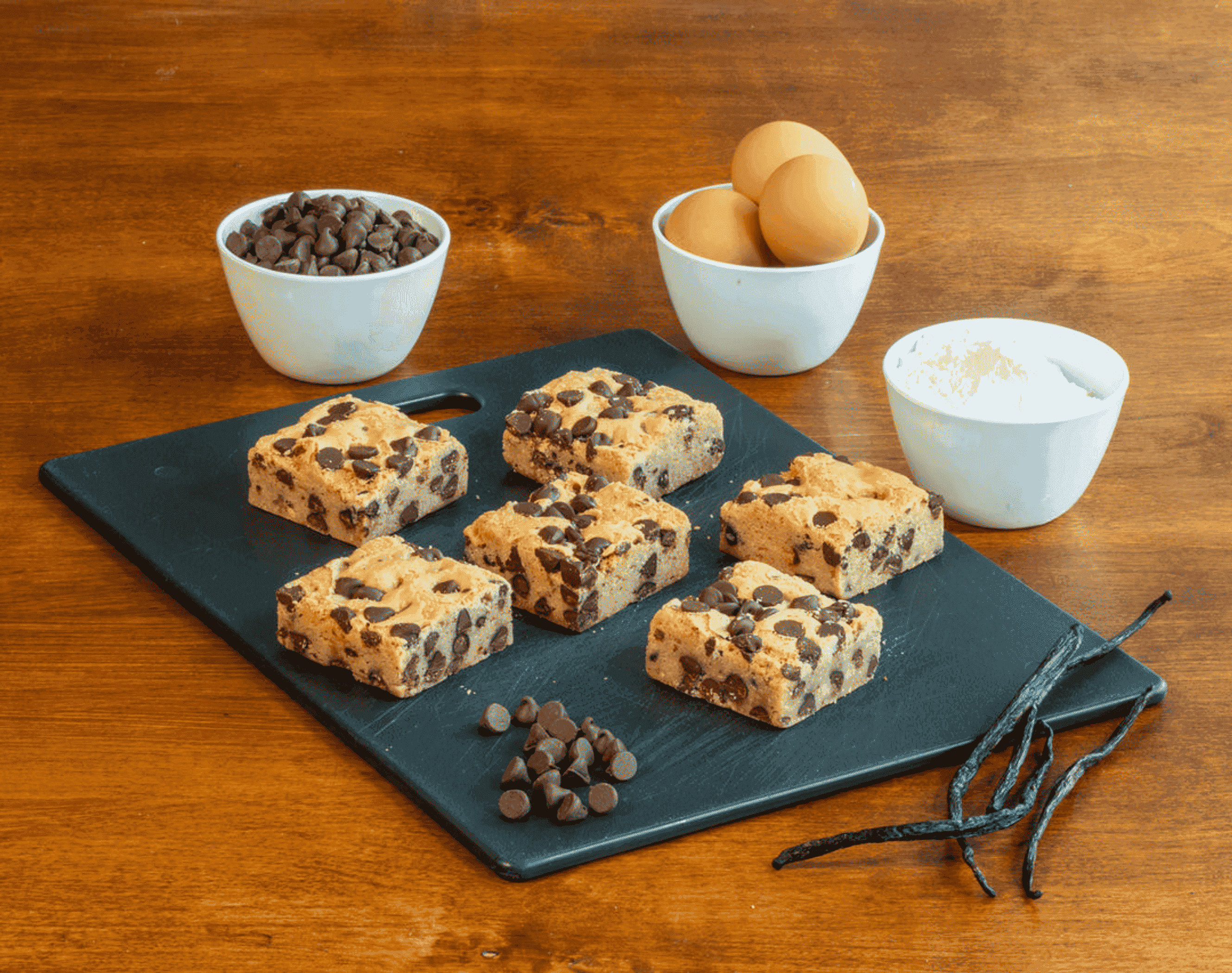 Assorted brownie blondie squares with dark chocolate chips on a serving board.