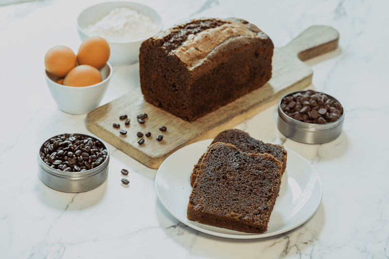 Chocolate cappuccino bread loaf and slices on board with chocolate chips and eggs