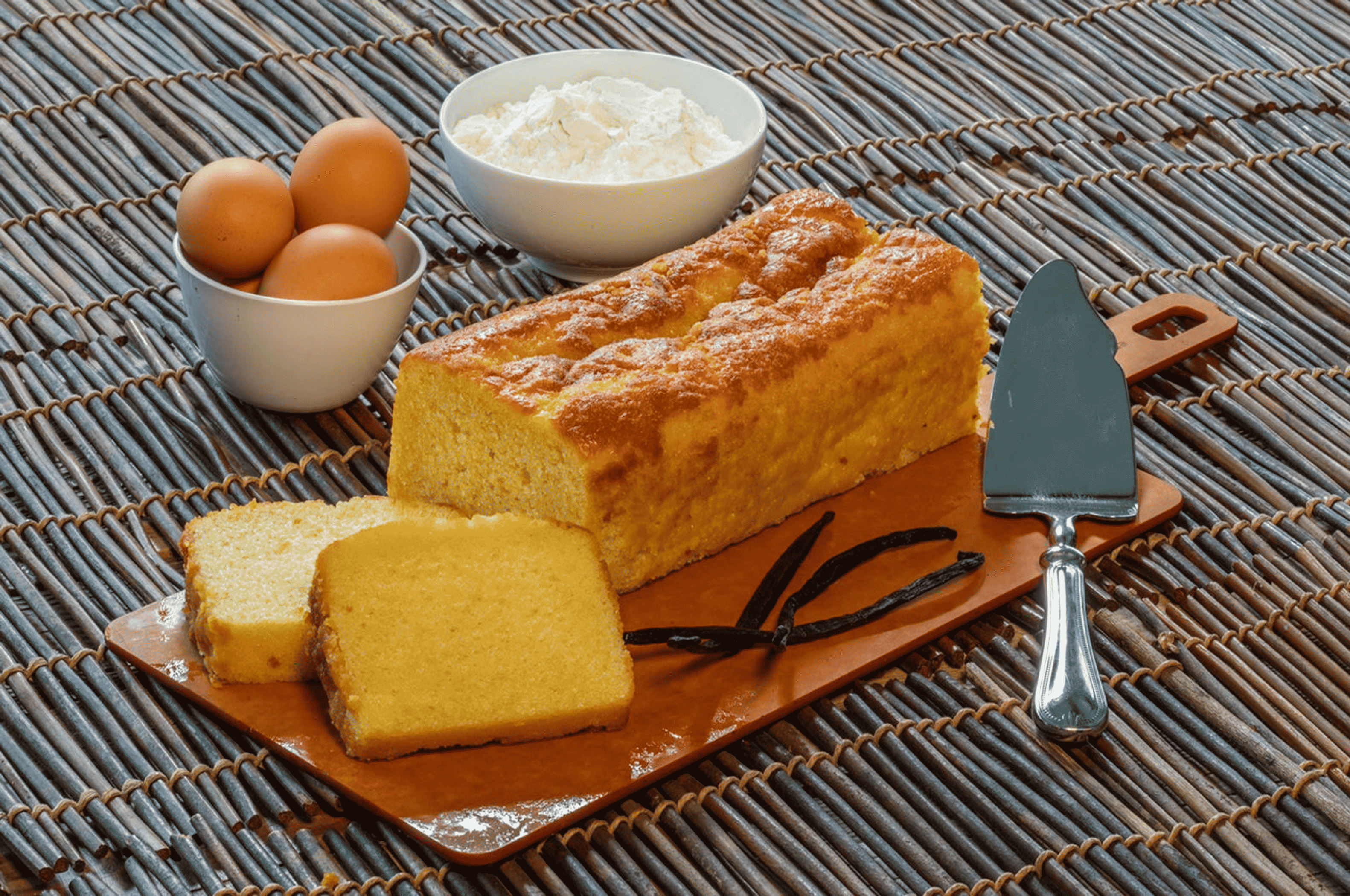 Vanilla pound cake slices on board with vanilla bean accents and eggs visible