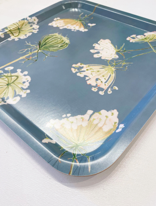 Teal square serving tray, close-up of cream and green flower illustrations on surface