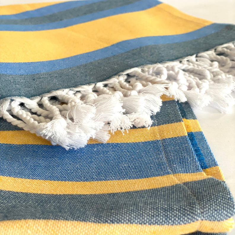 Turkish towel in blue, yellow, and white plaid with thick fringe border
