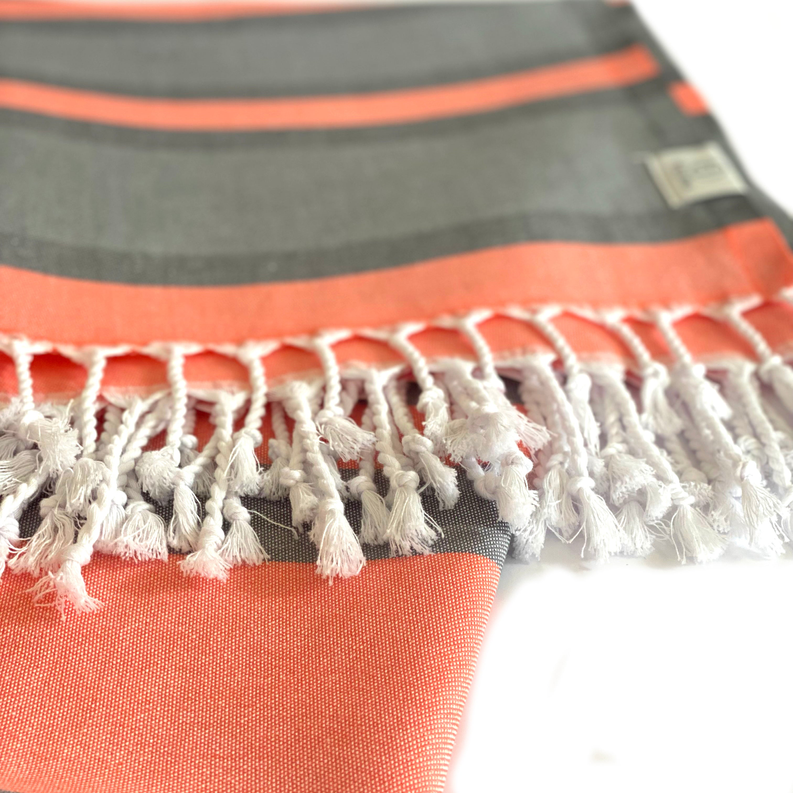 Gray Turkish towel with orange stripe border and white fringed tassels