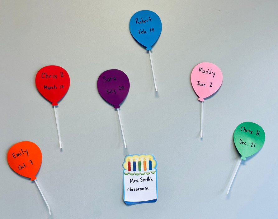 Heart-shaped balloon cut-outs with names and a small cake cut-out centerpiece