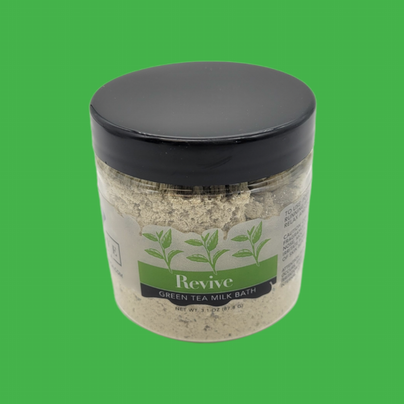 Milk bath soak jar with green tea revive label, black lid, pale powder inside.