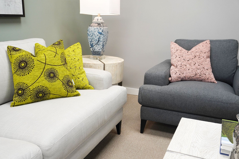 Decorative throw pillows with yellow-green and pink leaf-and-circle patterns on a sofa