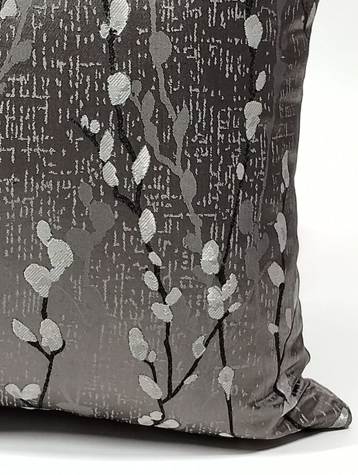 Dark gray throw pillow cover with silver branch and dot pattern, visible side seam.