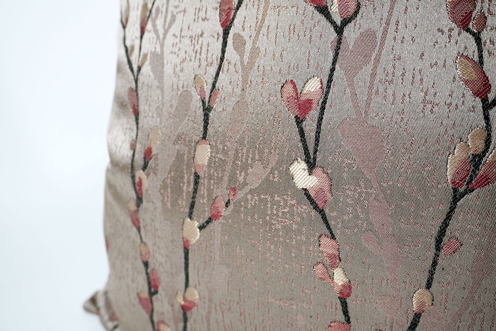 Taupe throw pillow cover with red and white branch-and-dot motif, close-up fabric texture.