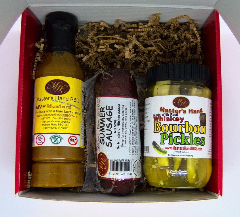 Open red gift set with BBQ sauce bottle, sausage, and bourbon pickles jar inside