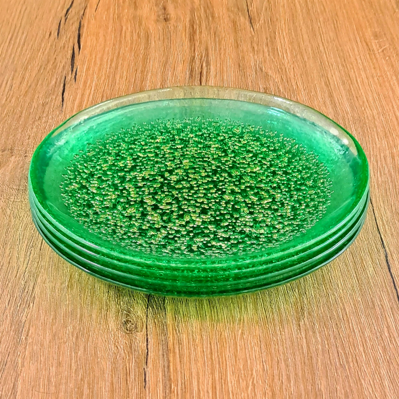 Stack of emerald glass dinner plates with gold speckled glaze, round top view.