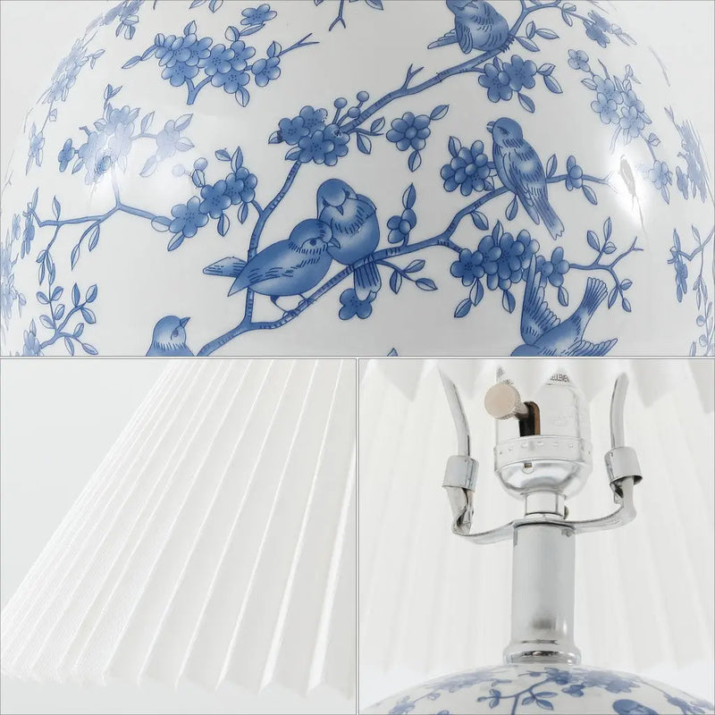Blue and white porcelain lamp with bird and flower design, featuring a pleated white shade and silver base.