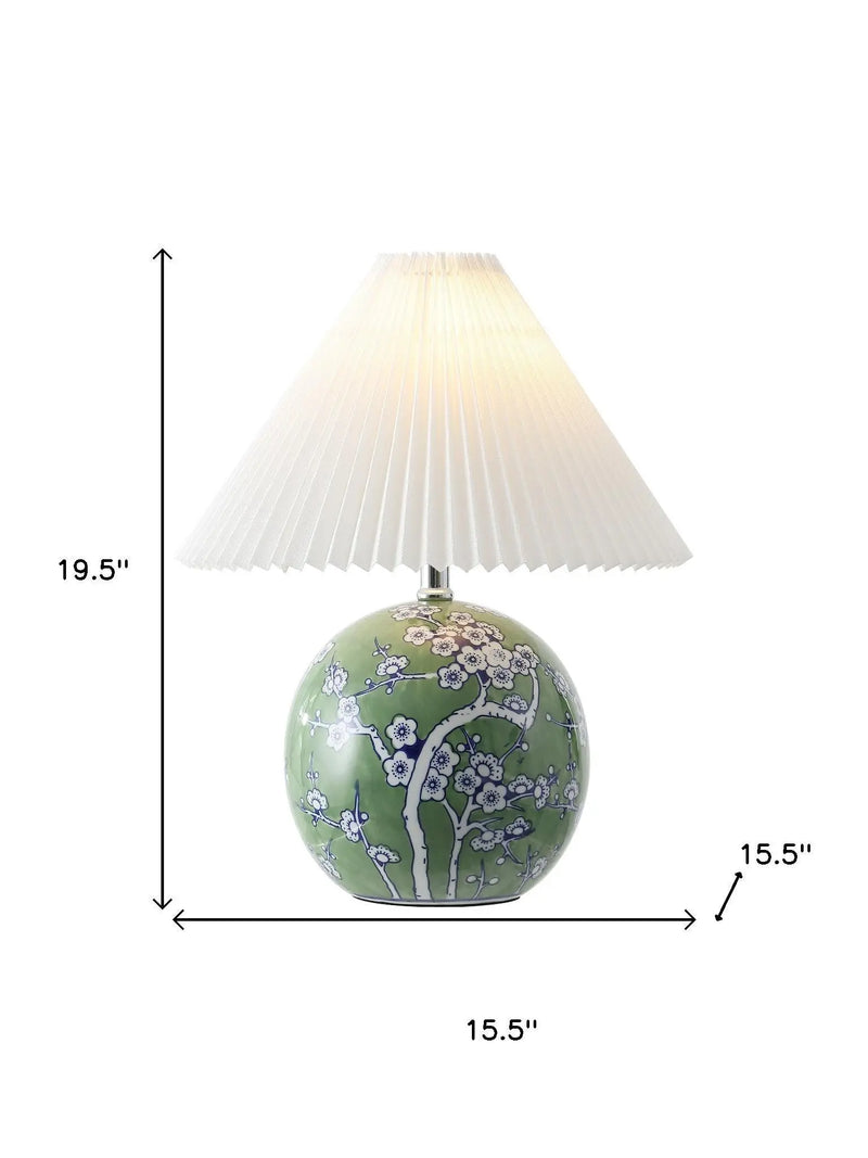 Green ceramic lamp with floral design and white pleated shade, height 19.5", width 15.5". Perfect for stylish decor.
