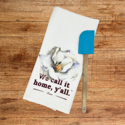 White kitchen towel with magnolia flower artwork and “We call it home, y’all.” text