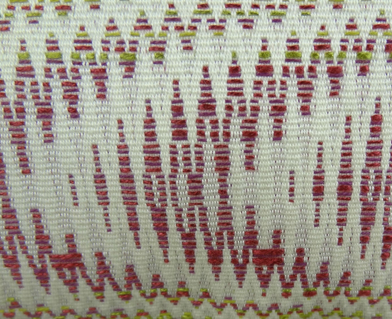 Close-up fabric of ivory pillow with embroidered wave pattern in beet and green