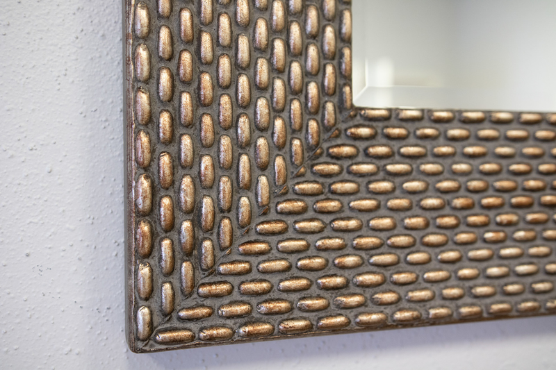 Corner detail of dark textured wood mirror frame with raised woven pattern