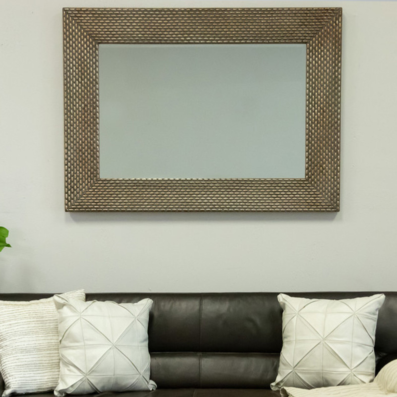 Rectangular wall mirror with textured dark wood frame above a dark sofa