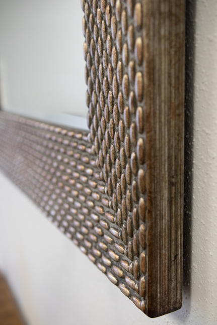 Close-up of dark wood frame edge with woven texture and raised pattern