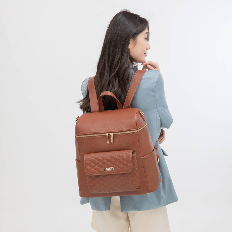 Caramel brown leather diaper backpack with quilted front pocket and top zipper