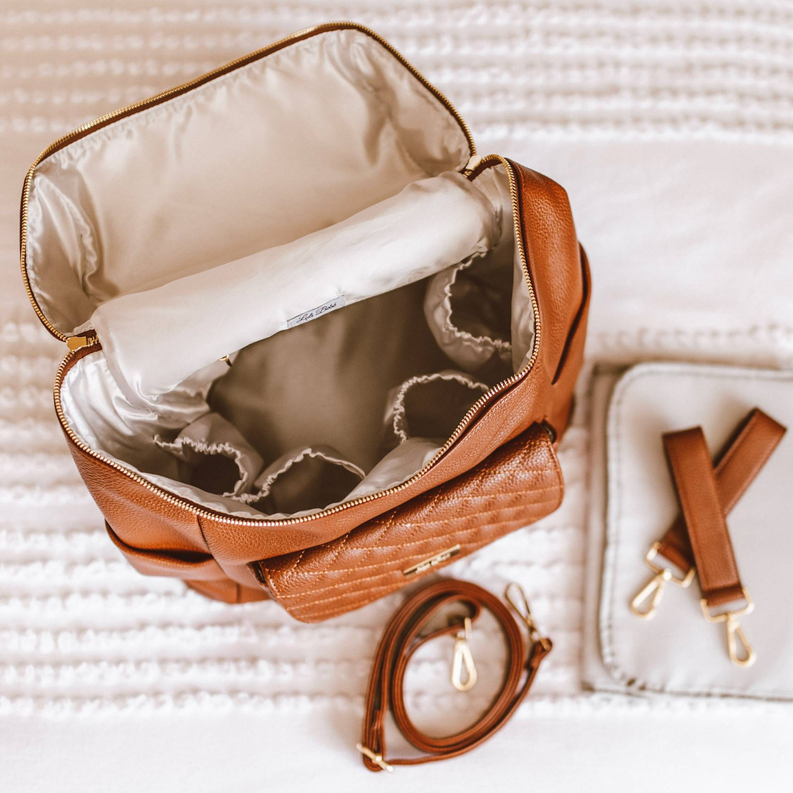 Caramel brown diaper bag backpack open with white insulated lining and zip compartments