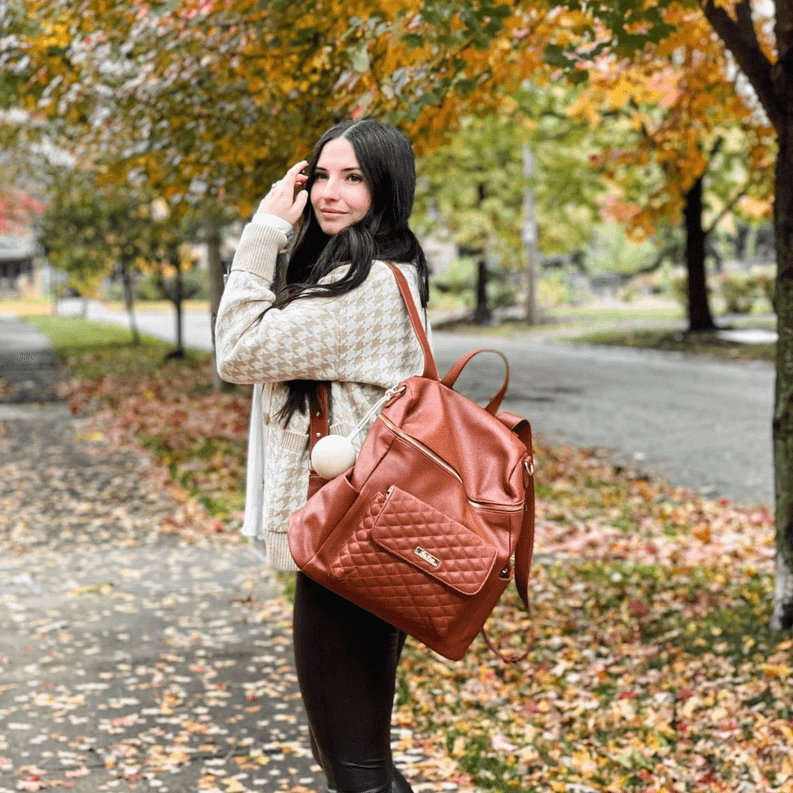 Caramel brown diaper bag with quilted front pocket and top handles, open zip close.